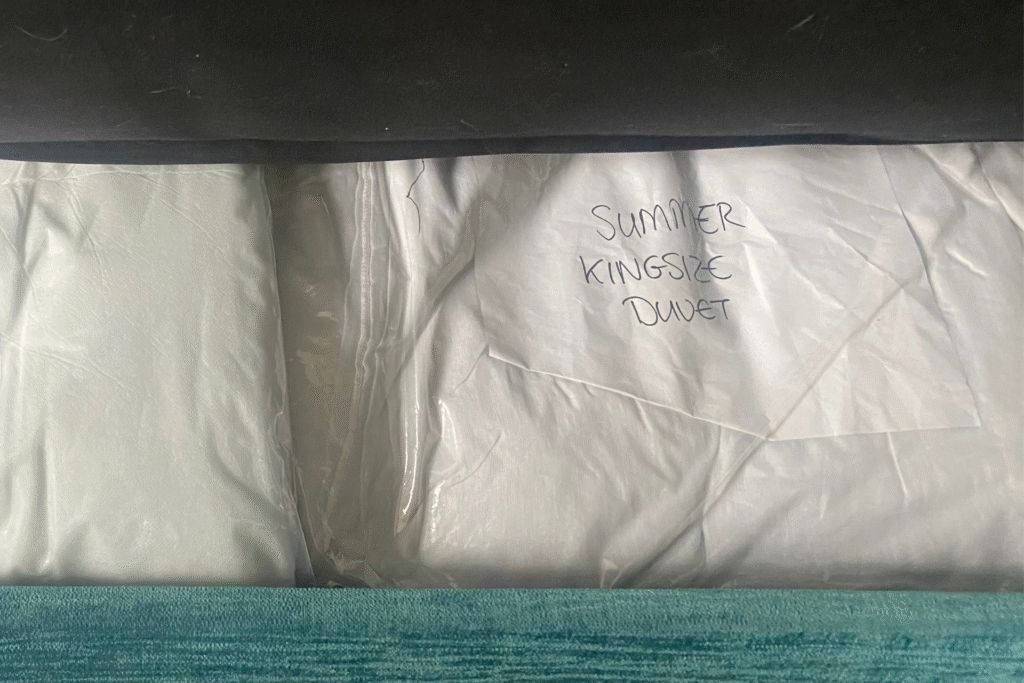 Photo of a duvet stored in a vacuum bag under a sofa bed, with the size and weight clearly labelled on it .