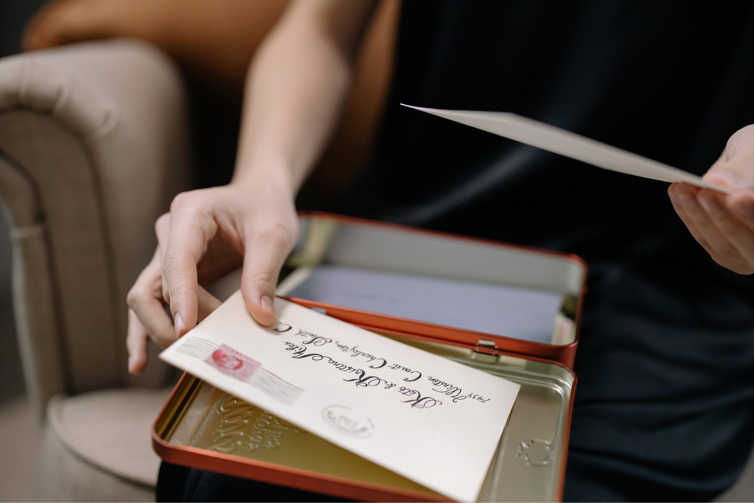 Photo of a womens hand holding a hand written letter, which she has just taken out of a box of keepsakes